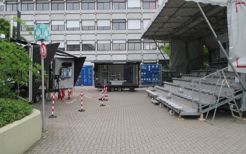 eine unbesetzte aufgebaute Tribüne, im Hintergrund der Demonstrationsanhänger der Fa. Geberit